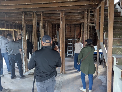 academy participants touring a residential home under reconstruction. The building is just rough construction, no sheetrock or trade work complete